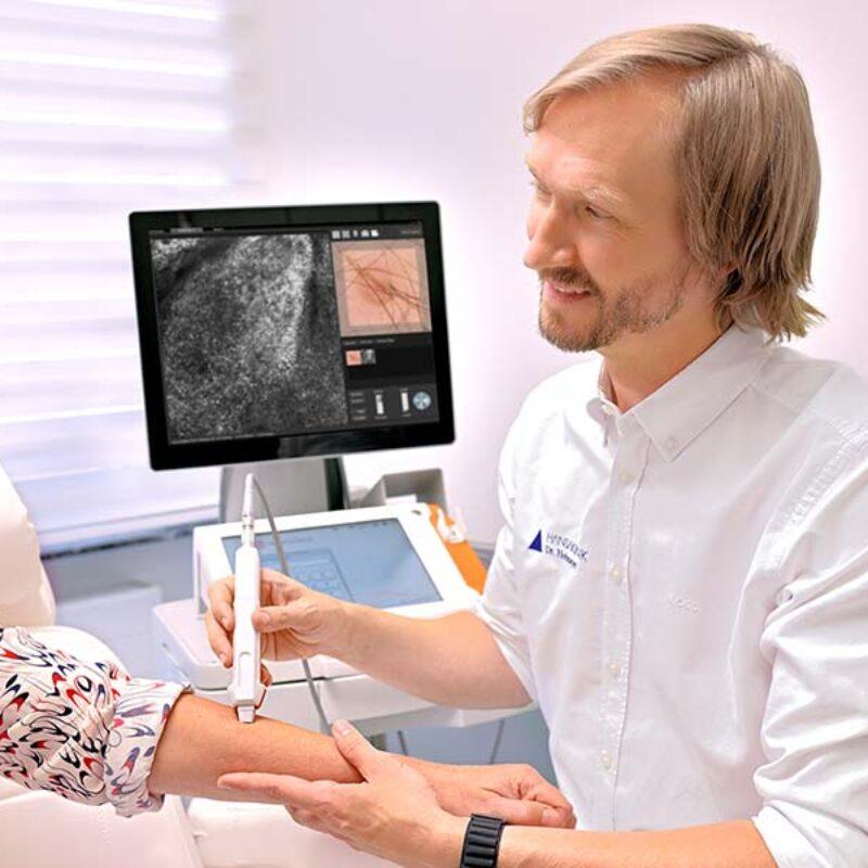Hautarzt in einer Hautklinik untersucht die Haut einer Parientin auf Hautkrebs